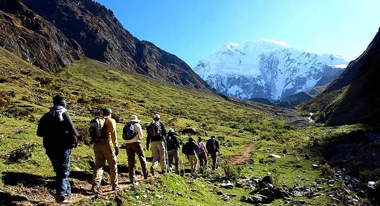 Grupo de trekkers en el sendero del Camino Inca atravesando los Andes peruanos rumbo a Machu Picchu, con el nevado Salkantay al fondo